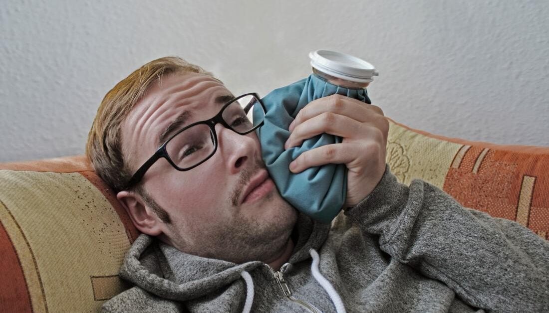 a man using a cold compress as tooth extraction aftercare