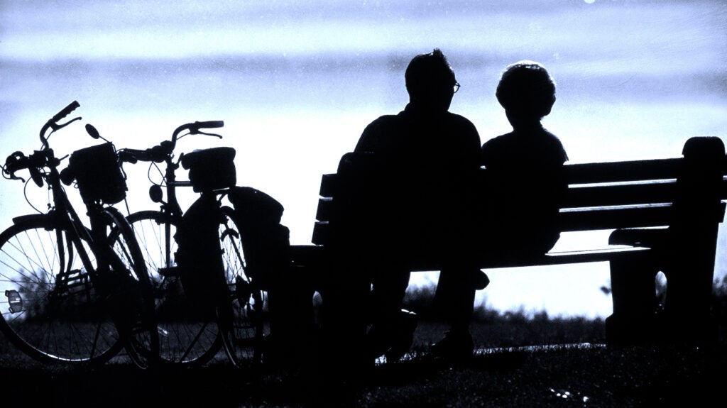A silhouette of people on a bench