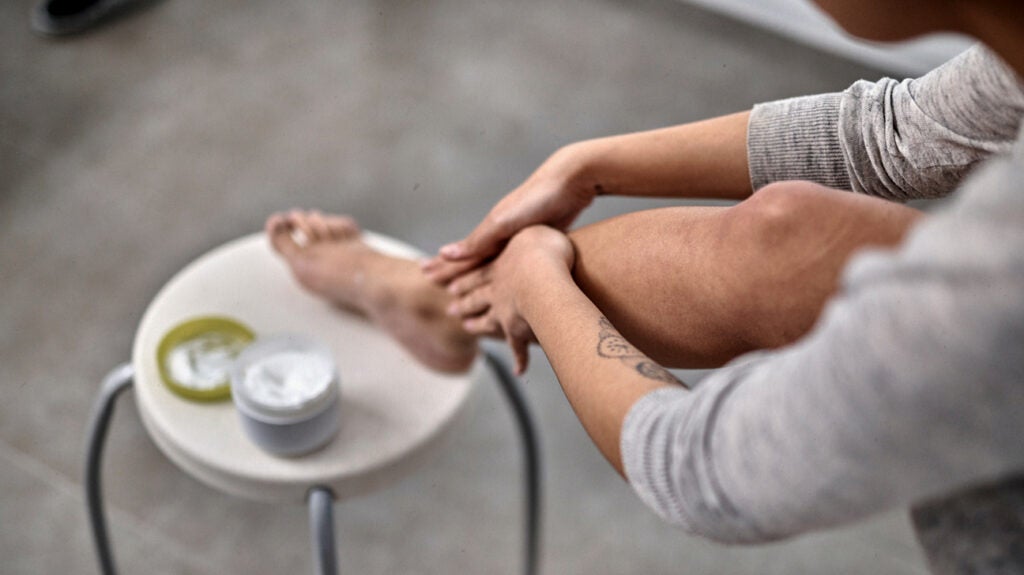 A person applying a cream to their leg.