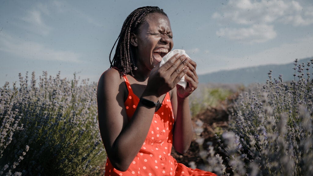 A woman sneezing in a field
