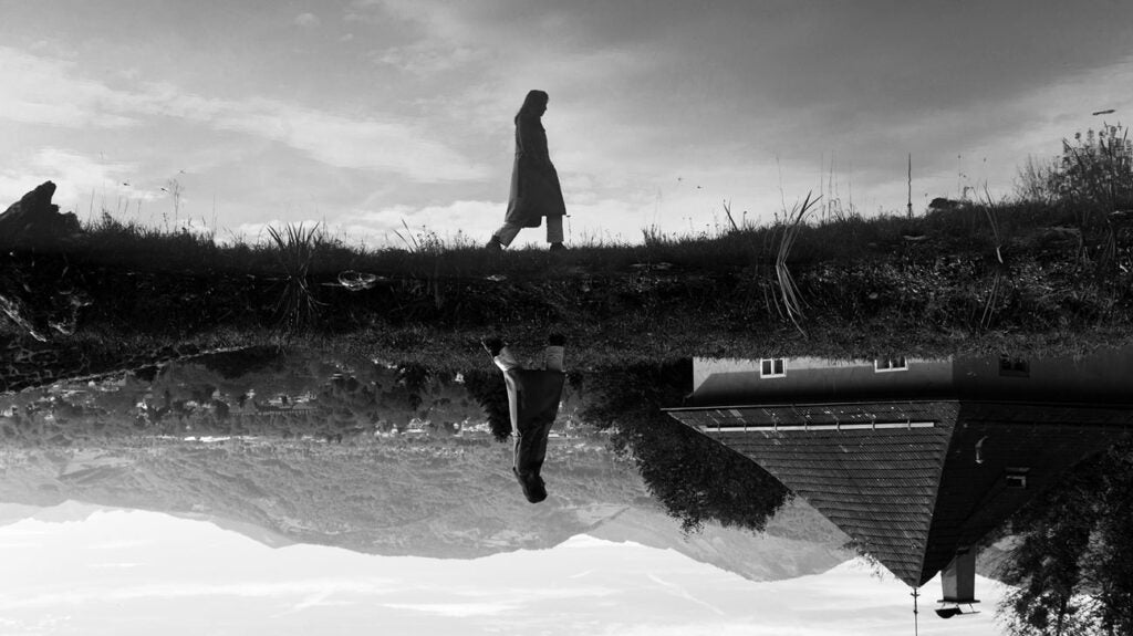 A person walking alone next to a lake.