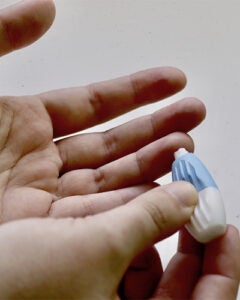 A close up photograph of a Medical News Today editor completing a finger prick blood test against a white background.