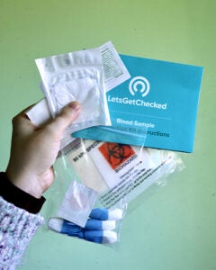 A Medical News Today editor holding the contents of a LetsGetChecked test against a green wall.